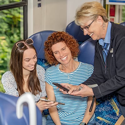 evb-kapmagne2024_motiv_immer-gut-begleitet_web_Q fröhliche Fahrgastbetreuerin und zwei Fahrgäste